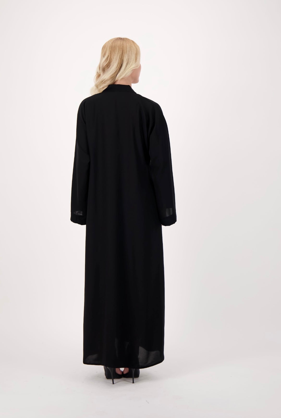 Front-opening black abaya made from soft, flowy Nida fabric, featuring a button-down design, loose fit, and full-length sleeves, worn by a model and displayed against a neutral background.