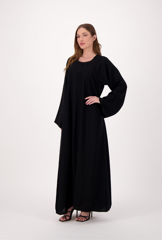 Plain black abaya made from soft, flowy Nida fabric, featuring a loose fit and full-length sleeves, worn by a model and displayed against a neutral background.