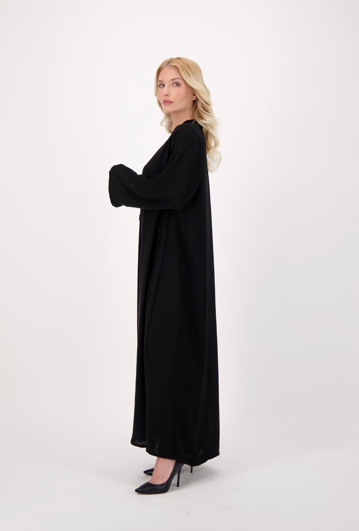 Front-opening black abaya made from soft, flowy Nida fabric, featuring a button-down design, loose fit, and full-length sleeves, worn by a model and displayed against a neutral background.
