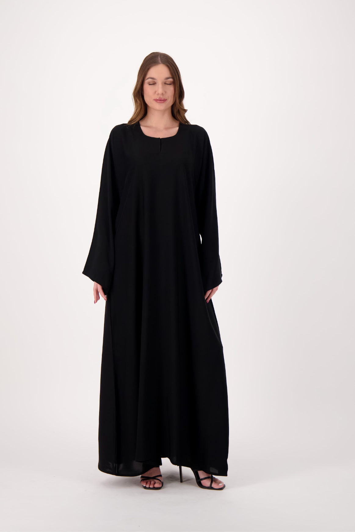 Plain black abaya made from soft, flowy Nida fabric, featuring a loose fit and full-length sleeves, worn by a model and displayed against a neutral background.