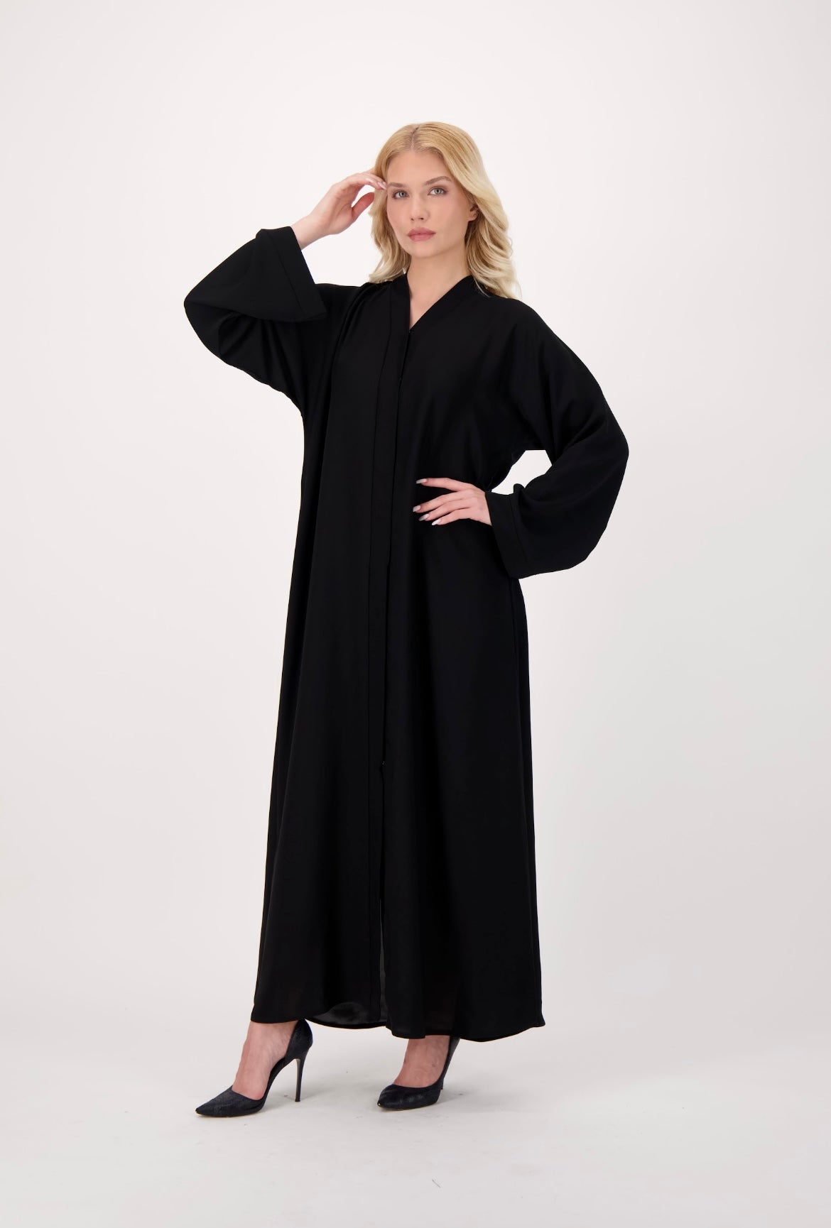 Front-opening black abaya made from soft, flowy Nida fabric, featuring a button-down design, loose fit, and full-length sleeves, worn by a model and displayed against a neutral background.