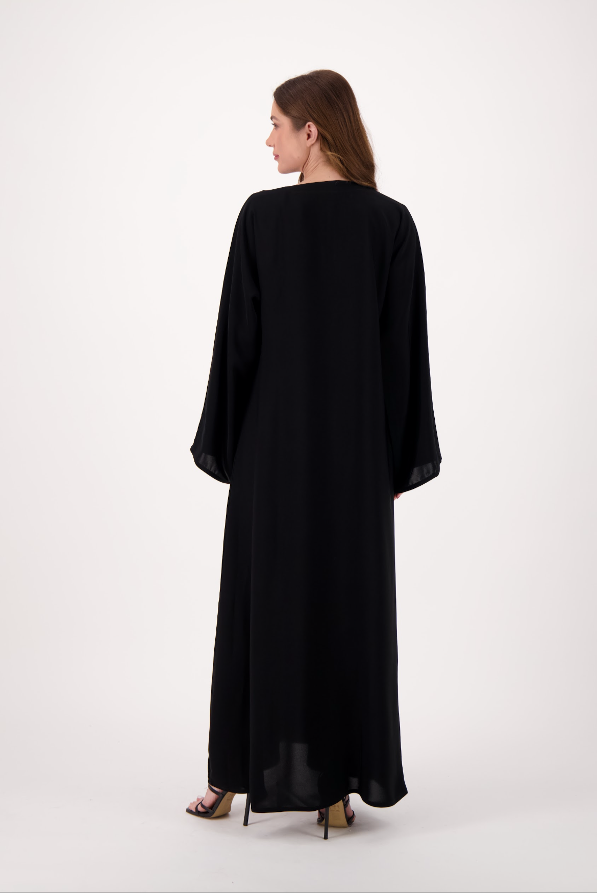 Plain black abaya made from soft, flowy Nida fabric, featuring a loose fit and full-length sleeves, worn by a model and displayed against a neutral background.