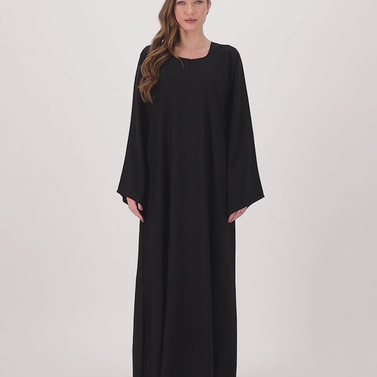 Plain black abaya made from soft, flowy Nida fabric, featuring a loose fit and full-length sleeves, worn by a model and displayed against a neutral background.