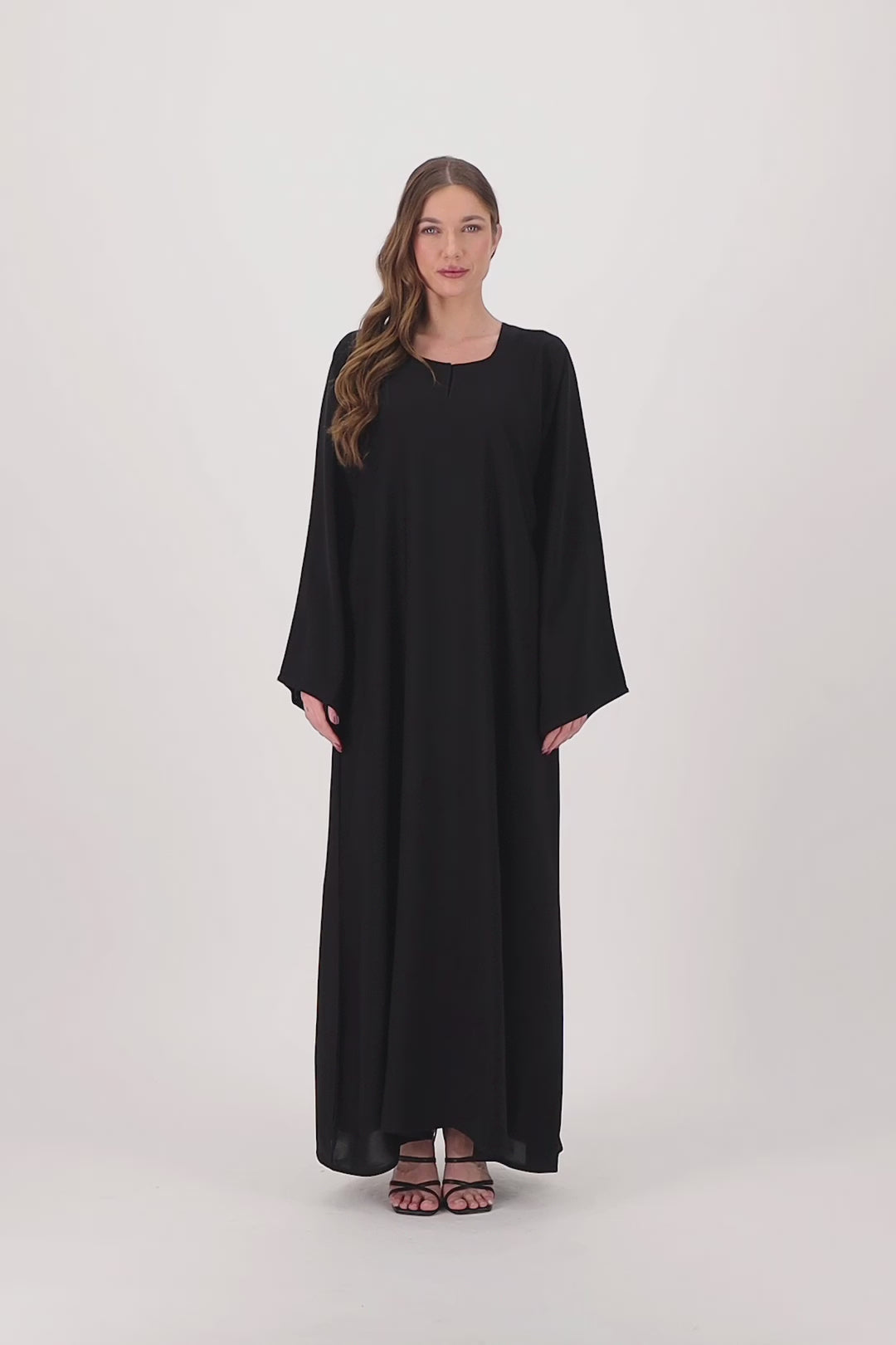 Plain black abaya made from soft, flowy Nida fabric, featuring a loose fit and full-length sleeves, worn by a model and displayed against a neutral background.